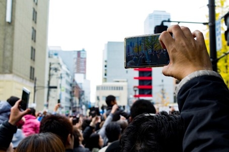 スマートフォンを掲げる傍観者の様子